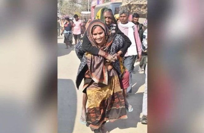महाकुंभ मेले में बुजुर्ग सास को अपनी पीठ पर लेकर चलती दिखी महिला